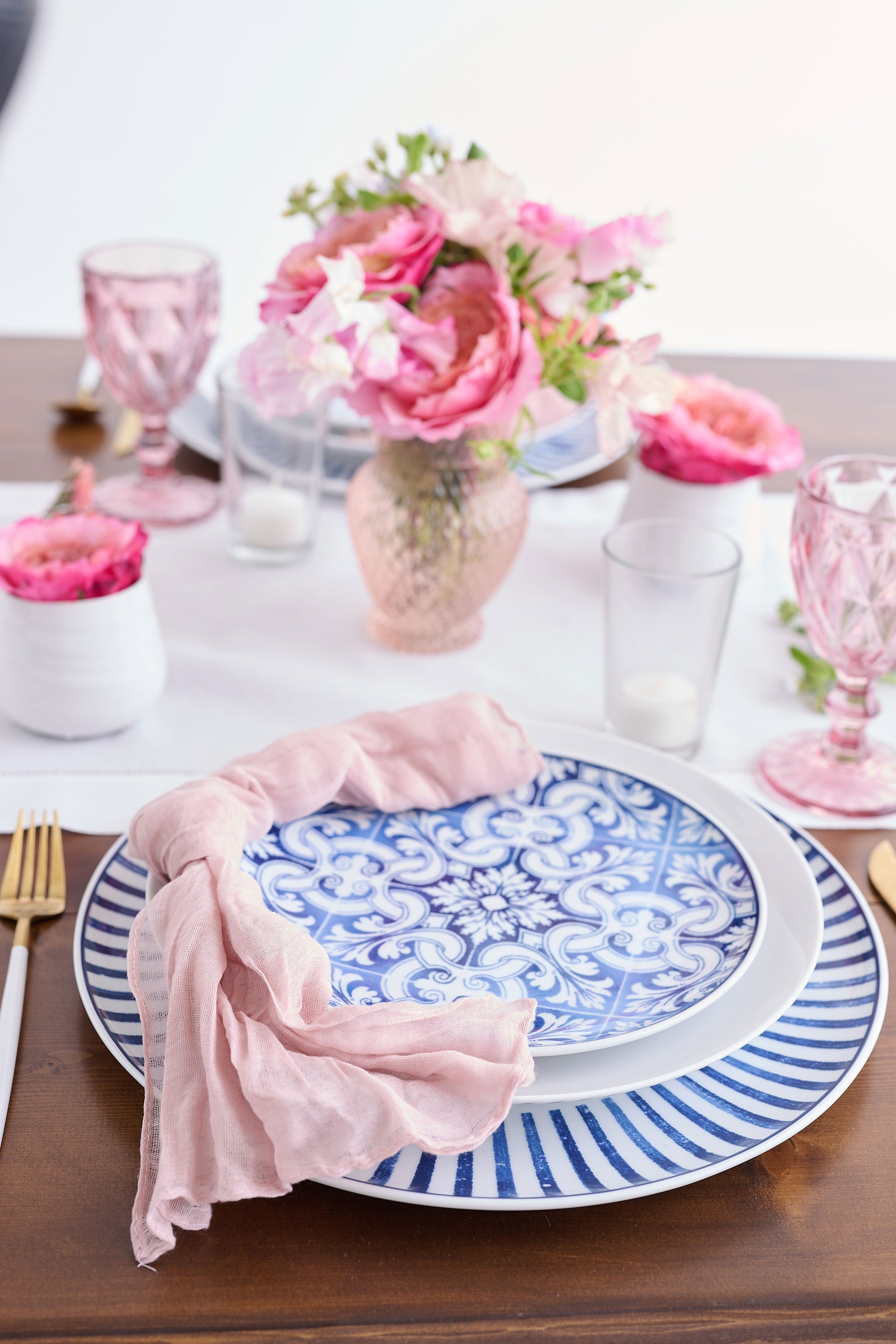 Tabletop setting with blue and white pattern dishes with pink florals and gold hardware.