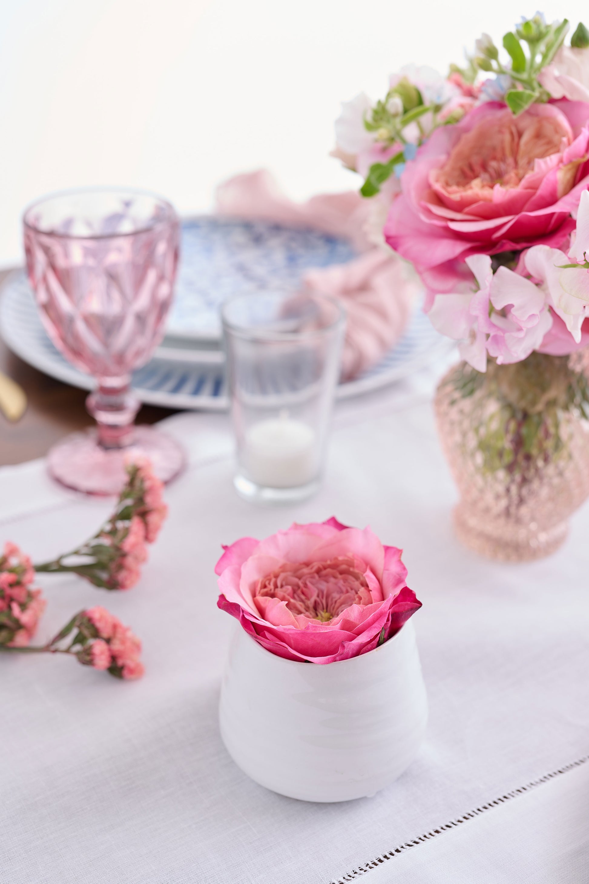 Tabletop setting with blue and white pattern dishes with pink florals and gold hardware.