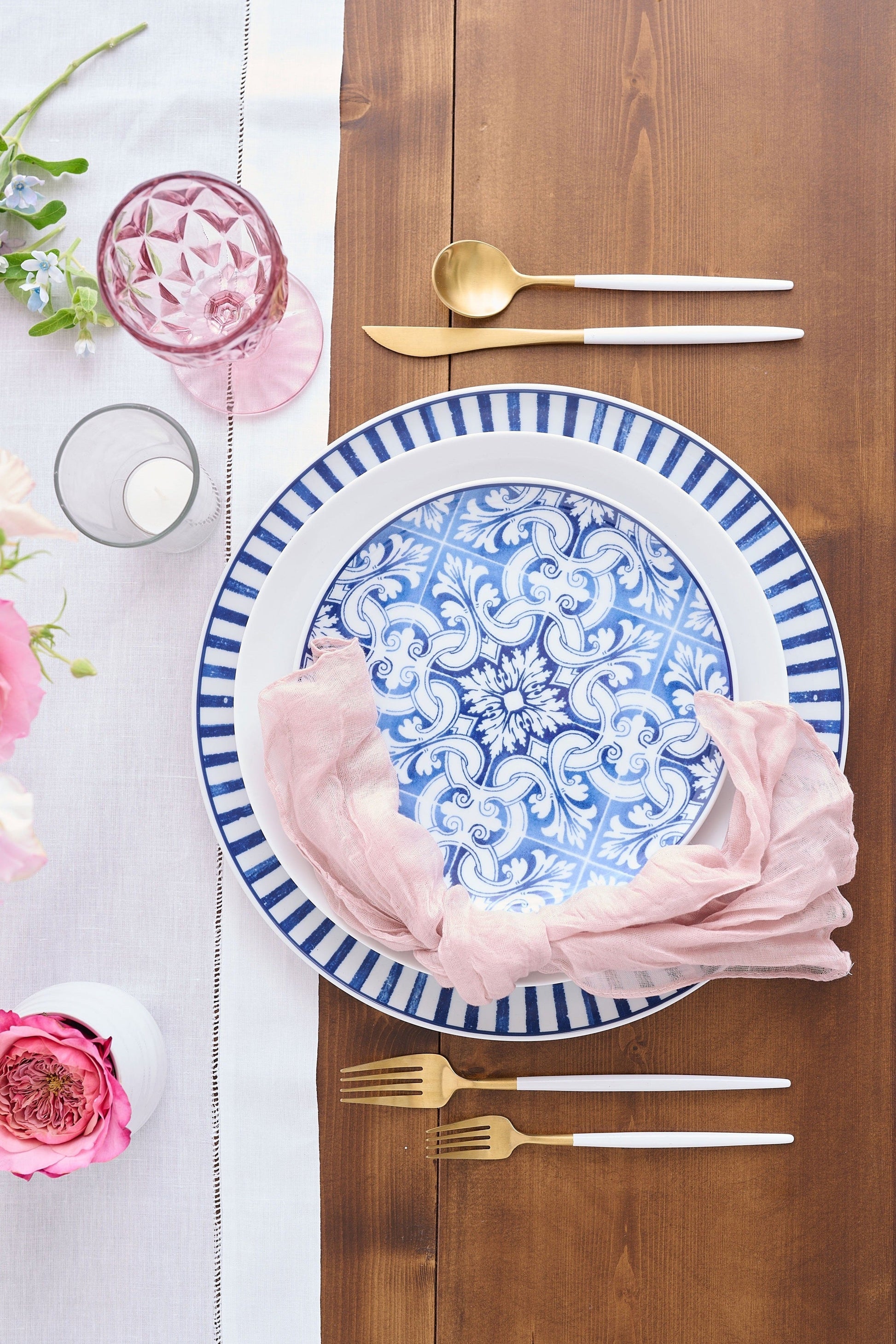 Tabletop setting with blue and white pattern dishes with pink florals and gold hardware.