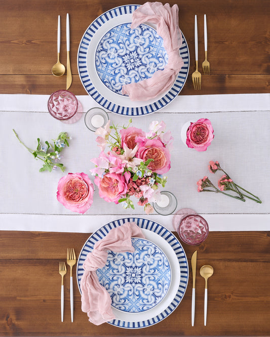Tabletop setting with blue and white pattern dishes with pink florals and gold hardware.